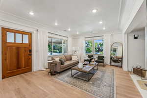 Living room with light hardwood / wood-style flooring and ornamental molding