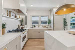 Kitchen with sink, decorative light fixtures, double oven range, and light hardwood / wood-style floors