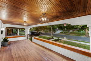 Unfurnished sunroom with wooden ceiling and a notable chandelier