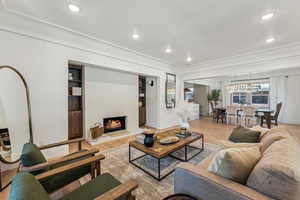 Living room with light hardwood / wood-style floors, a chandelier, and ornamental molding