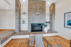 Unfurnished living room featuring a brick fireplace and light hardwood / wood-style floors