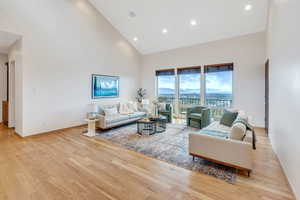 Living room with high vaulted ceiling and light hardwood / wood-style flooring