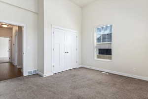 Unfurnished bedroom with carpet, a closet, and a high ceiling