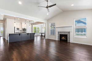 Unfurnished living room featuring ceiling fan, vaulted ceiling, and dark hardwood / wood-style flooring