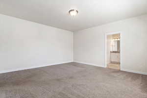 Unfurnished bedroom featuring ensuite bath and light carpet