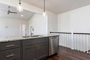 Kitchen with stainless steel dishwasher, sink, light stone counters, pendant lighting, and dark hardwood / wood-style flooring