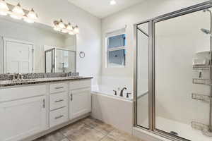 Bathroom featuring tile patterned floors, double sink vanity, and plus walk in shower