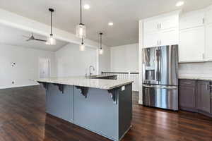 Kitchen with dark hardwood / wood-style flooring, tasteful backsplash, decorative light fixtures, and stainless steel refrigerator with ice dispenser