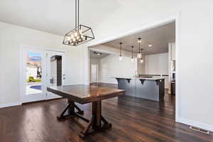 Dining space featuring vaulted ceiling, an inviting chandelier, and dark wood-type flooring