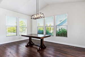 Dining area with lofted ceiling, dark hardwood / wood-style flooring, and an inviting chandelier