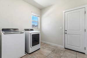 Laundry room with washer and clothes dryer and light tile patterned floors