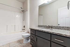 Full bathroom featuring tile patterned flooring, toilet, vanity, and shower / tub combination