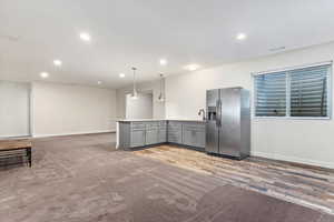 Kitchen featuring gray cabinets, hanging light fixtures, hardwood / wood-style flooring, stainless steel fridge with ice dispenser, and sink