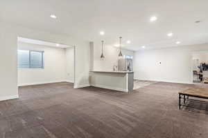 Unfurnished living room featuring dark colored carpet