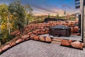 Patio terrace at dusk featuring a hot tub