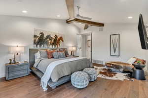 Bedroom with vaulted ceiling with beams and hardwood / wood-style flooring