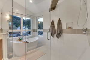 Bathroom featuring tile walls, vaulted ceiling, plus walk in shower, and tile patterned floors