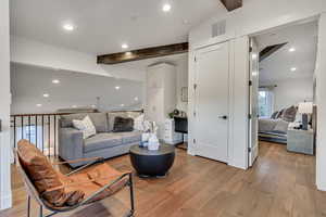 Living room featuring light wood-type flooring and vaulted ceiling with beams