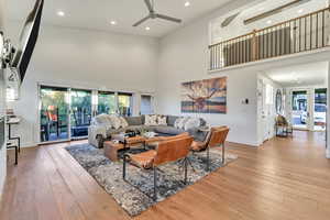 Living room with ceiling fan, high vaulted ceiling, and light hardwood / wood-style floors