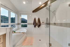 Bathroom with independent shower and bath, vanity, and tile walls