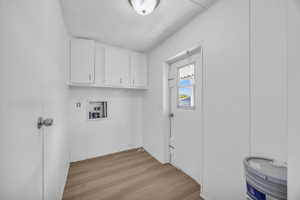 Washroom featuring light hardwood / wood-style flooring, washer hookup, and cabinets