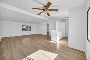 Bonus room with ceiling fan, vaulted ceiling with beams, and light hardwood / wood-style flooring