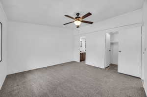 Unfurnished bedroom with a walk in closet, carpet, ensuite bath, a closet, and ceiling fan