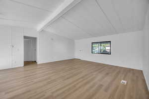 Interior space with light hardwood / wood-style flooring and lofted ceiling with beams