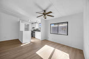 Unfurnished dining area with ceiling fan, light hardwood / wood-style floors, vaulted ceiling, and sink