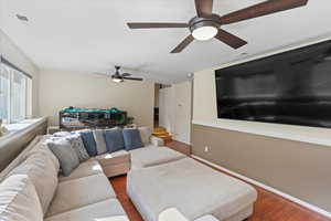 Living room with ceiling fan and dark wood-type flooring