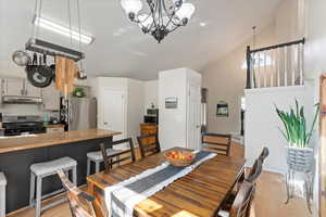 Dining space with high vaulted ceiling, an inviting chandelier, and light hardwood / wood-style floors