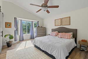 Bedroom featuring ceiling fan, high vaulted ceiling, and light hardwood / wood-style floors