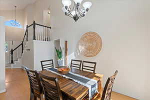 Dining area with light wood-type flooring, high vaulted ceiling, and a chandelier