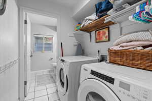 Laundry area with light tile patterned flooring and washing machine and clothes dryer