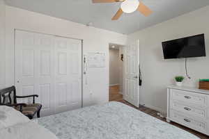 Bedroom with ceiling fan, a closet, and dark wood-type flooring