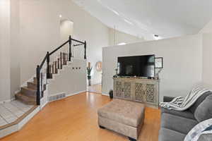 Living room with high vaulted ceiling and wood-type flooring