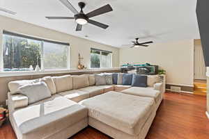 Living room with ceiling fan and dark hardwood / wood-style floors