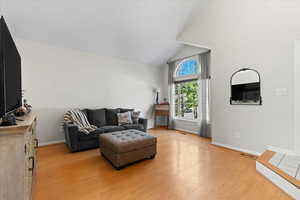 Living room with light hardwood / wood-style floors and lofted ceiling