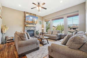 Living room with a fireplace, ceiling fan, and light hardwood / wood-style floors