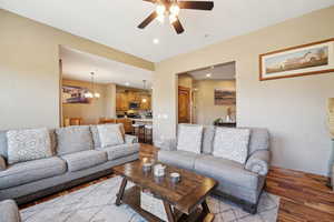 Living room with ceiling fan with notable chandelier and hardwood / wood-style floors