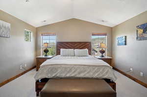 Bedroom with light colored carpet and vaulted ceiling