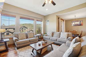 Living room featuring ceiling fan with notable chandelier and hardwood / wood-style floors