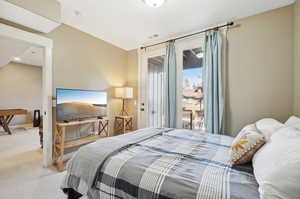 Bedroom with light colored carpet, vaulted ceiling, and access to exterior