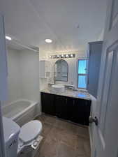 Full bathroom with shower / bathing tub combination, vanity, tile patterned floors, a textured ceiling, and toilet