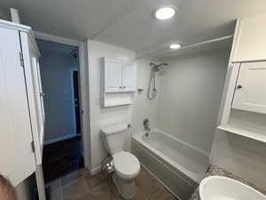 Bathroom with tile patterned flooring, toilet, and shower / washtub combination