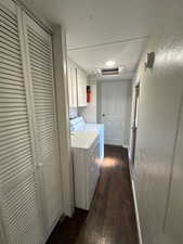 Laundry room with independent washer and dryer, cabinets, and hardwood / wood-style floors