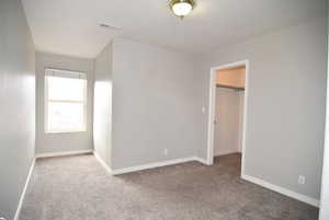 Unfurnished bedroom with carpet flooring, a walk in closet, and a closet