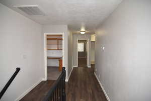 Hall with dark hardwood / wood-style flooring and a textured ceiling