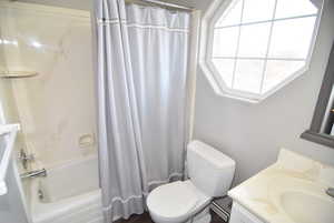 Full bathroom with vanity, shower / bath combination with curtain, and toilet