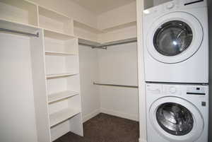 Laundry area with dark carpet and stacked washer / dryer